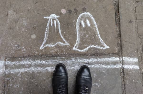 Looking down at two ghosts drawn on the ground with chalk.