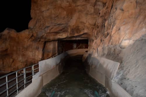 A point of view photograph of an old log flume ride, with the track running through fake rockwork.