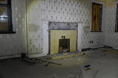 A flash photograph of a fireplace in a decaying building.